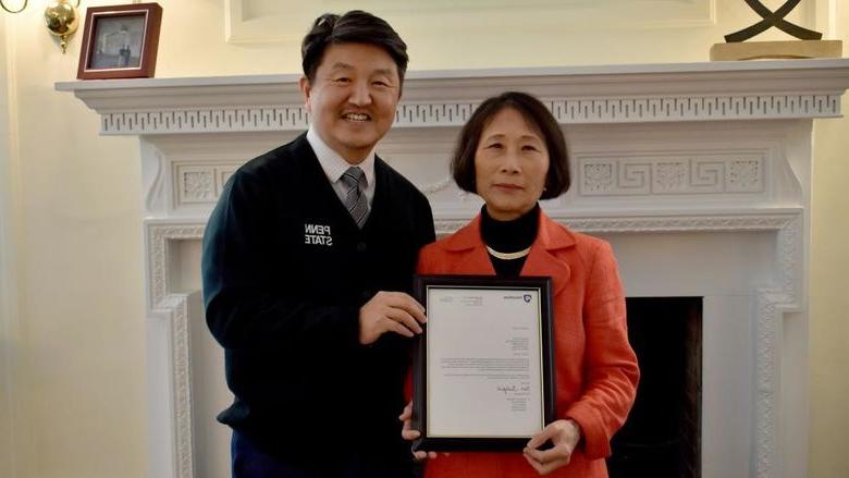 Penn State 杜波依斯 chancellor and chief academic officer Jungwoo Ryoo, 正确的, presents Pingjuan沃纳 with a framed copy of the letter certifying her as a distinguished professor, the highest professorial distinction at the University