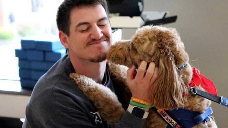 Penn State 杜波依斯 third-year student Jeff Romano enjoys the comfort a therapy dog gives him during one of the events of De-Stress Fest at Penn State 杜波依斯.