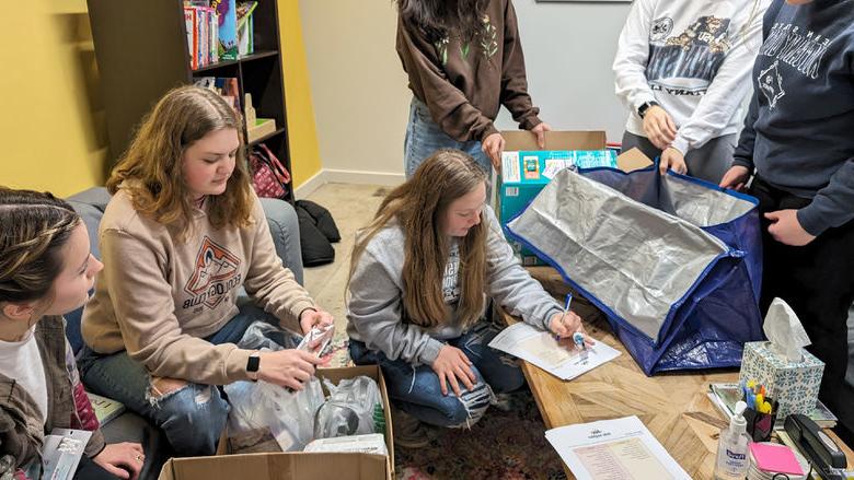 HDFS club members take inventory and organize items at Hello Neighbor during the process of making baby bags during their visit.